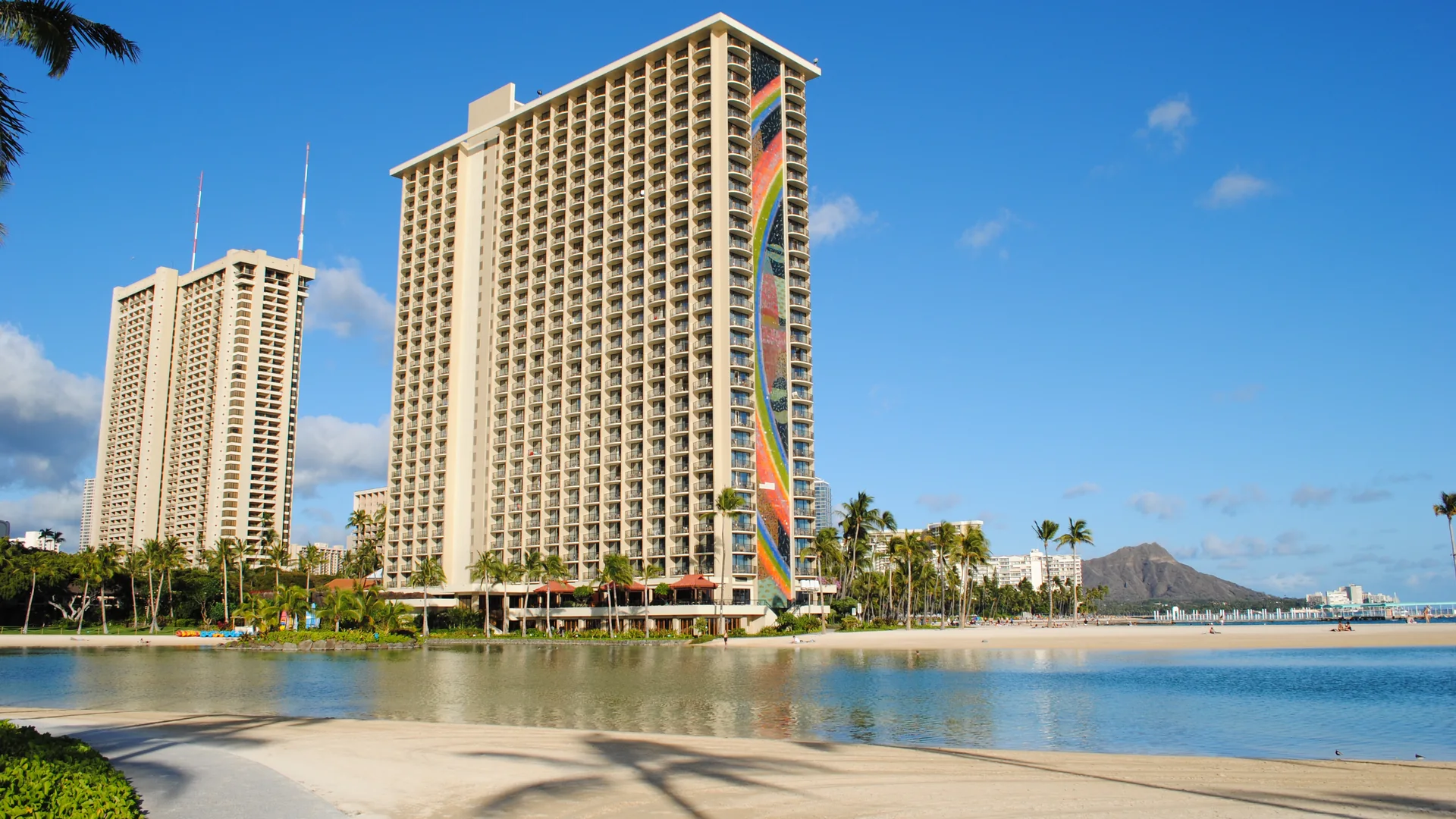 Hilton Hawaiian Village's Rainbow Tower beside its lagoon, with palm trees, the beach and Diamond Head in view